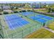 Aerial view of the community's blue tennis courts, shuffleboard court, manicured lawns, and surrounding buildings at 25555 Heritage Lake Blvd # 27, Punta Gorda, FL 33983