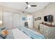 Bright bedroom featuring a ceiling fan, white closet doors, and a dresser with wall-mounted television at 2630 Tarpon Cove Dr # 212, Punta Gorda, FL 33950