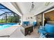 Screened patio area with bright blue furniture, a modern fire pit and views of the pool and landscaping at 3724 Bordeaux Dr, Punta Gorda, FL 33950