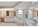 Bright bathroom features neutral paint, tiled floors, dual sinks, and soaking tub at 421 Strasburg Dr, Port Charlotte, FL 33954