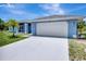 Charming blue home with a spacious driveway, attached garage, and well-maintained landscaping at 421 Strasburg Dr, Port Charlotte, FL 33954