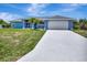 Charming single-story home with a two-car garage, well-maintained lawn, and freshly painted light blue exterior at 421 Strasburg Dr, Port Charlotte, FL 33954