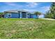 Well-manicured lawn and lovely landscaping complement this charming blue home's exterior at 421 Strasburg Dr, Port Charlotte, FL 33954
