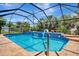 Sparkling screened-in pool with blue tile, brick trim, and landscaped surroundings at 421 Strasburg Dr, Port Charlotte, FL 33954