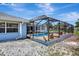 Outdoor screened-in pool with clear blue water and patio, surrounded by gravel and lush landscaping at 421 Strasburg Dr, Port Charlotte, FL 33954