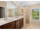 Bright bathroom with dual sinks, a glass-enclosed shower, and a window at 4268 Leesburg Ave, North Port, FL 34288