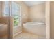 Well-lit bathroom featuring a soaking tub, separate shower, and large window at 4268 Leesburg Ave, North Port, FL 34288