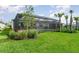 Expansive backyard with lush lawn, landscaping, and a screened-in pool at 42771 Valley Brooks St, Punta Gorda, FL 33982