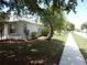 Sidewalk view of a white stucco home with well-maintained landscaping and mature trees in a peaceful neighborhood at 500 Winwood Ct, Port Charlotte, FL 33954