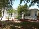 Charming home featuring a well-manicured front lawn with garden beds, mature trees, and a white stucco exterior at 500 Winwood Ct, Port Charlotte, FL 33954