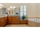 Bright bathroom featuring granite countertops, wood cabinets, tub and window at 5221 Blackjack Cir, Punta Gorda, FL 33982