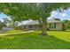Beautiful home with a lush green lawn, a screened porch, and plenty of shade trees at 5221 Blackjack Cir, Punta Gorda, FL 33982