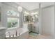 Bright bathroom featuring double sinks, vanity with granite counters, a soaking tub, and a separate shower at 5273 Crestline Ter, Port Charlotte, FL 33981