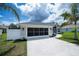 Beautiful single-story home with a screened garage, arched windows, and a lush green lawn adorned with palm trees at 591 San Ambrosio St, Punta Gorda, FL 33983