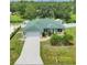 Aerial view of a one-story home with a green roof, a driveway, and a lush green lawn at 7280 Muncey Rd, North Port, FL 34291