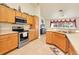Bright kitchen with stainless steel appliances, oak cabinets, tile floor and a wine-themed decor at 7280 Muncey Rd, North Port, FL 34291