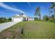 Charming single-story home with a well-maintained lawn, a red front door, and an attached two-car garage at 7345 Ellis Ln, Port Charlotte, FL 33981