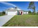 Charming single-Gathering home featuring a two-car garage, well-maintained lawn, and welcoming red front door at 7345 Ellis Ln, Port Charlotte, FL 33981