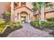 Entrance to a multi-story building with a brick path leading to an arched doorway and manicured landscaping at 90 Vivante Blvd # 202, Punta Gorda, FL 33950