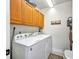 Functional laundry room with white washer/dryer units and wooden cabinets above at 90 Vivante Blvd # 202, Punta Gorda, FL 33950