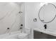 Bathroom featuring modern fixtures, marble-style tile in the shower, and a round mirror above the sink at 165 Ingram Blvd, Rotonda West, FL 33947