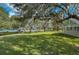 Expansive backyard area with lush green grass, mature trees, and a gazebo overlooking the serene pond offering tranquility at 1318 Red Oak Ln, Port Charlotte, FL 33948