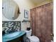 Bathroom showcasing a stylish blue glass vessel sink, unique mosaic tile, and decorative shower curtain at 1318 Red Oak Ln, Port Charlotte, FL 33948