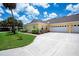 Side view of the home showcasing the attached garage, manicured lawn, and walkway to the front entrance at 1318 Red Oak Ln, Port Charlotte, FL 33948