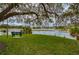Scenic lake view from a grassy area with mature trees and a bench at 1318 Red Oak Ln, Port Charlotte, FL 33948
