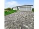 Long driveway leading to a modern home, showing a gray roof, lawn, and a two-car garage at 13406 Chenille Dr, Port Charlotte, FL 33981