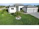 Landscaped front yard featuring lush grass, palm trees, and a modern white house with a gray roof at 13406 Chenille Dr, Port Charlotte, FL 33981