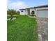 Lush green lawn, palm trees, and a modern home create a welcoming curb appeal with a paved driveway at 13406 Chenille Dr, Port Charlotte, FL 33981