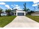 Newly built single Gathering home featuring a modern exterior, palm trees, well-manicured lawn, and a driveway at 14372 Tugwell Ave, Port Charlotte, FL 33953