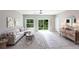 Bright living room featuring a comfortable couch, large windows, a ceiling fan, and a decorative area rug at 14372 Tugwell Ave, Port Charlotte, FL 33953