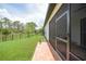 A glimpse of the brick patio and screened lanai with views of the green backyard and tall trees from the side of the house at 15261 Mille Fiore Blvd, Port Charlotte, FL 33953