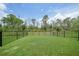Expansive, well-maintained fenced backyard with lush green grass and views of the surrounding tall trees at 15261 Mille Fiore Blvd, Port Charlotte, FL 33953