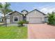 Charming single-Gathering home with a stone facade, brick driveway, and a well-manicured lawn at 15261 Mille Fiore Blvd, Port Charlotte, FL 33953