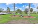 Landscaped front yard with palm trees and circular red mulch beds creating a serene and inviting curb appeal at 15652 Havana Cir, Port Charlotte, FL 33981