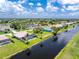 Aerial view of a home with a screened pool, next to a canal, surrounded by tropical landscaping and a lawn at 167 & 169 Marker Rd, Rotonda West, FL 33947