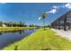 Water view from backyard featuring a tropical palm tree, lawn, and screened in lanai at 167 & 169 Marker Rd, Rotonda West, FL 33947