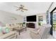 Living room with carpet, a ceiling fan, TV, and neutral colored furniture with tropical patterned pillows at 167 & 169 Marker Rd, Rotonda West, FL 33947
