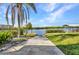 Concrete path leads to backyard waterfront with dock, boat lift, and lush landscaping at 18566 Arapahoe Cir, Port Charlotte, FL 33948