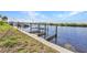 Dock with boat lift situated along the waterfront on a clear day at 18566 Arapahoe Cir, Port Charlotte, FL 33948
