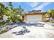 Charming home with a two-car garage, palm trees, and mature landscaping at 18566 Arapahoe Cir, Port Charlotte, FL 33948