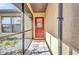 Screened front porch with tiled floor, leading to a charming red front door at 18566 Arapahoe Cir, Port Charlotte, FL 33948