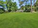 View of the expansive backyard with lush green grass and a screened-in pool in the distance at 2131 Heasley Rd, Englewood, FL 34223