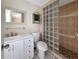 A bathroom features a white vanity, toilet, and glass block shower with neutral tile flooring at 2131 Heasley Rd, Englewood, FL 34223