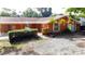 Inviting one-story home features an orange exterior, manicured shrubs, and a gravel driveway at 2131 Heasley Rd, Englewood, FL 34223