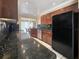 Kitchen with granite counters, wood cabinets, and black appliances at 2131 Heasley Rd, Englewood, FL 34223
