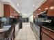 Modern kitchen features dark wood cabinetry, black countertops and stainless steel appliances at 2131 Heasley Rd, Englewood, FL 34223